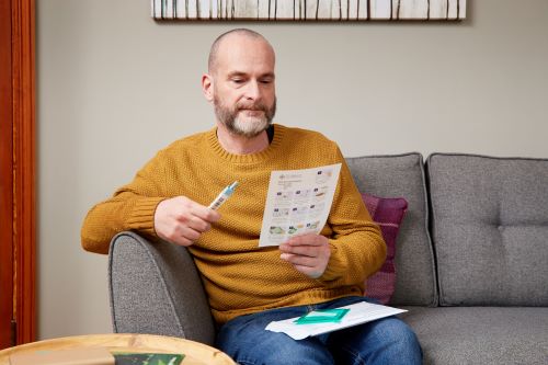 Photo showing a man using a Faecal Immunochemical Test (FIT) kit from Wales